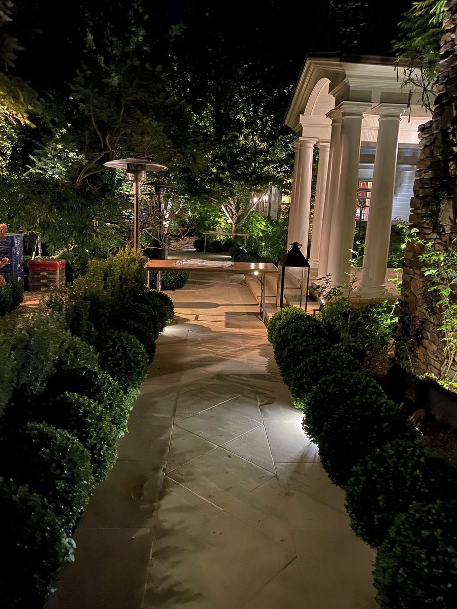 Boxwood walk toward lit colonnade