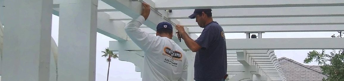 Two technicians installing a fixture on a white pergola